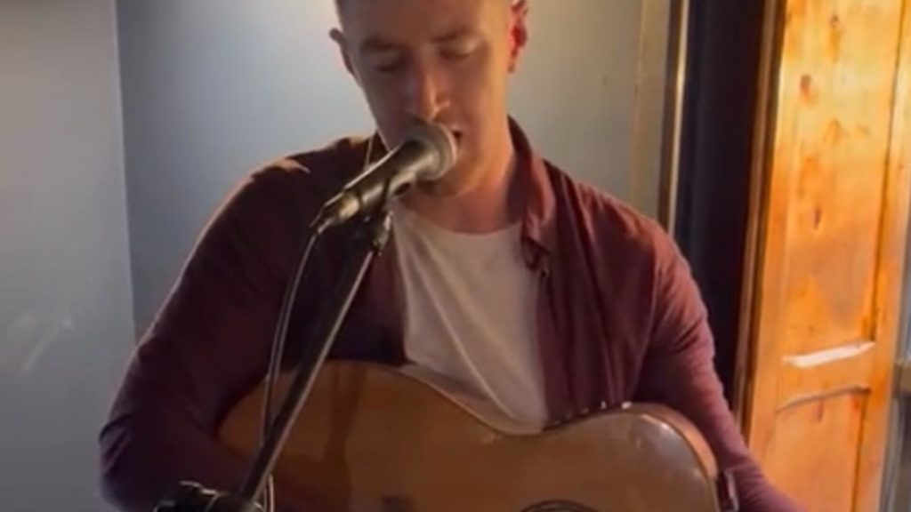 Paul Luby stands at a mic and sings