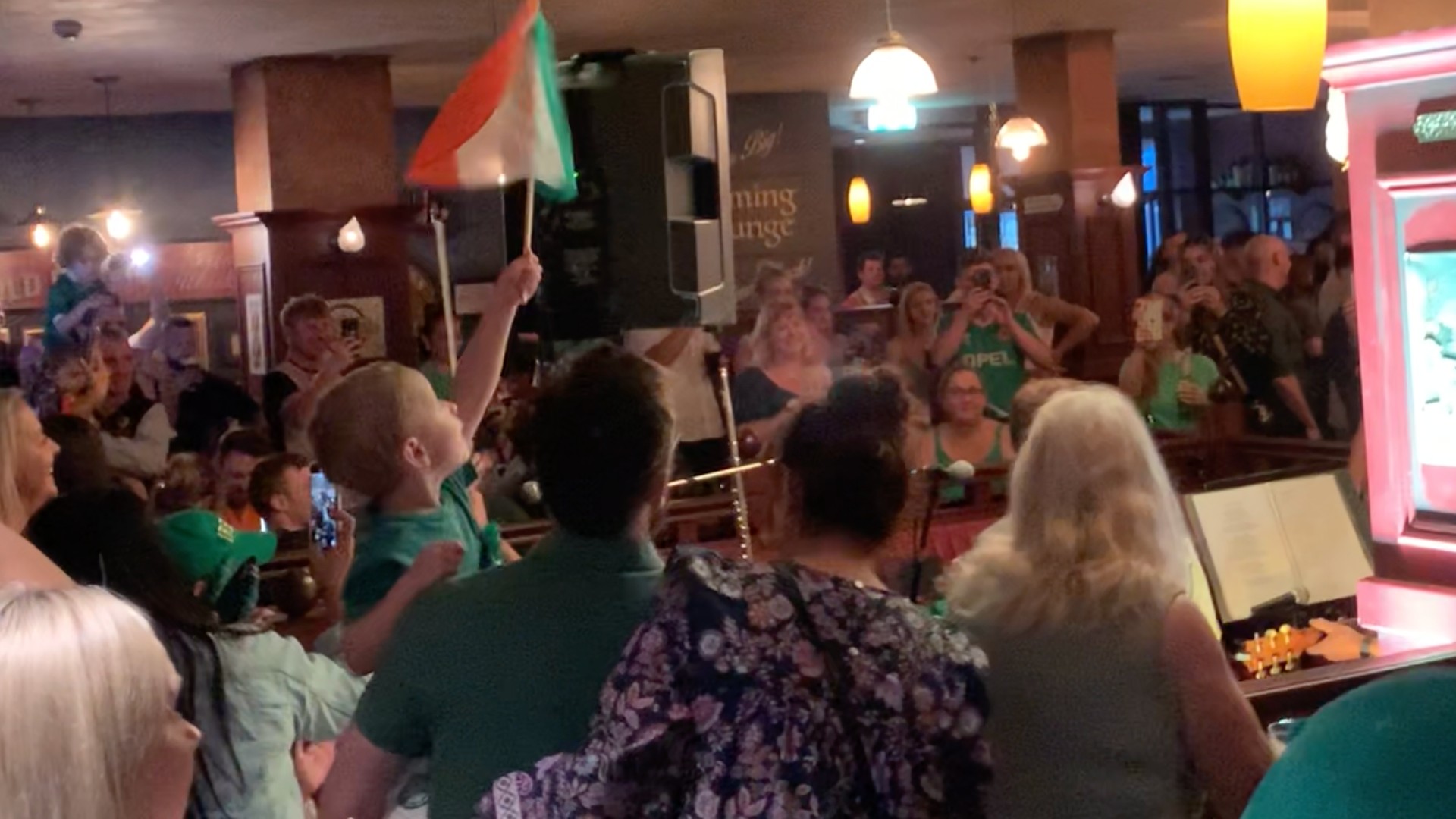 A crowd of Irish wave flags and sing at Southend Hotel